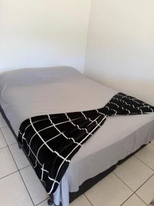 a bed with a black and white blanket on it at Pousada Helena e Heloá in Serra Negra +17 photos