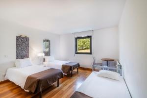 a white room with two beds and a window at HI Alvados - Pousada de Juventude in Alvados