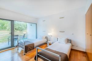 two beds in a room with a window at HI Alvados - Pousada de Juventude in Alvados