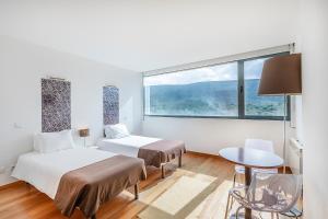 two beds in a room with a large window at HI Alvados - Pousada de Juventude in Alvados