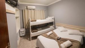 a small room with two beds and a shower at Pousada Ilha do Itacolomi in Penha
