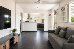 a living room with a couch and a kitchen at Villa 6 pers Jacuzzi Centre Guadeloupe in Petit-Bourg