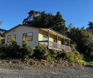 a house on a hill with trees and bushes at Raynbird Cottage in Dunedin
