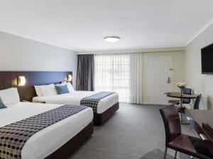 a hotel room with two beds and a desk at Mercure Wagga Wagga in Wagga Wagga