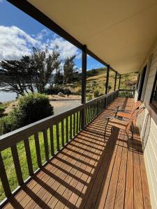 a wooden porch with benches on the side of a house at Raynbird Cottage in Dunedin