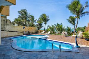 a swimming pool with a deck and palm trees at Atlântico Flat Beira Mar in Natal +8 photos