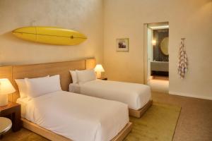 ein Schlafzimmer mit zwei Betten und einem Surfbrett an der Wand in der Unterkunft Surf Hotel in Torquay