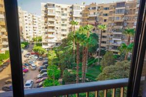 a balcony with a view of a parking lot with palm trees at 2 Bedrooms Spacious flat 7 mins to Airport in Cairo