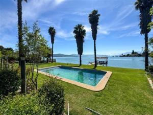 a swimming pool in the grass near the water with palm trees at El Estero Lago Rapel in El Estero