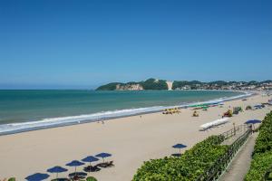 a beach with umbrellas and people on the beach at Atlântico Flat Beira Mar in Natal