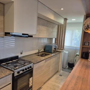 a kitchen with white cabinets and a stove top oven at Depto nivel ejecutivo in Villa Regina