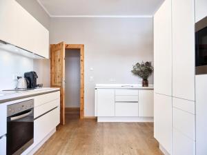 a white kitchen with white cabinets and a wooden floor at Stadtchalet Forsthaus in Kitzbühel