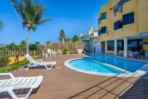 a resort with a pool and chairs and a building at Atlântico Flat Beira Mar in Natal