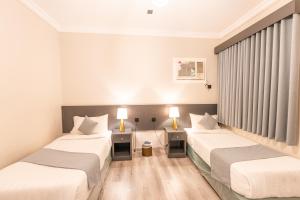 two beds in a hotel room with two lamps at عالم الضيافة in Al ‘Azīzīyah