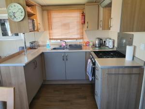 a small kitchen with a sink and a clock at 3-Bed Caravan Sleeps 8 with Enclosed Decking in Fleetwood