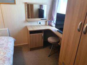 a room with a desk with a computer and a monitor at 3-Bed Caravan Sleeps 8 with Enclosed Decking in Fleetwood