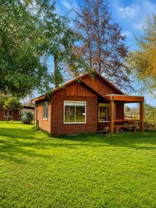 a small house in a yard with a green lawn at Turismo La Isla in Salto del Laja