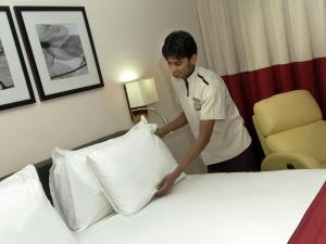 a man putting pillows on a bed in a hotel room at Novotel Suites Riyadh Olaya in Riyadh