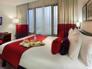 a hotel room with a bed with a tray of food on it at Novotel Suites Riyadh Olaya in Riyadh