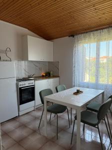 a kitchen with a white table and chairs and a window at Apartments and rooms by the sea Mandre, Pag - 3557 in Kolan