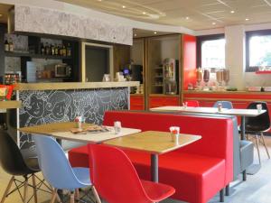a restaurant with red chairs and tables and a counter at ibis Soissons in Soissons