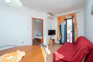 a living room with a red couch and a table at Apartments and rooms by the sea Jakisnica, Pag - 4160 in Lun