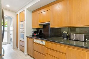 a kitchen with wooden cabinets and a black counter top at Mirage Resort Villa 169 with access to Sheraton Facilities in Port Douglas