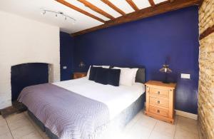 a bedroom with a large bed and a blue wall at The Old Coach house- a delightful home from home in Witney