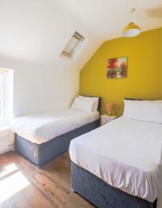 two beds in a room with a yellow wall at The Old Coach house- a delightful home from home in Witney +49 photos
