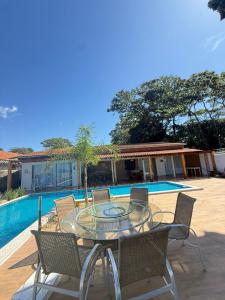 a patio with a glass table and chairs next to a pool at Maresia Beach House in Rio das Ostras +5 photos