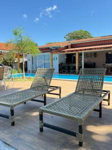two metal chairs sitting next to a swimming pool at Maresia Beach House in Rio das Ostras