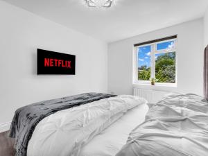 a white bedroom with a bed and a sign on the wall at LODGEselect in Thamesmead