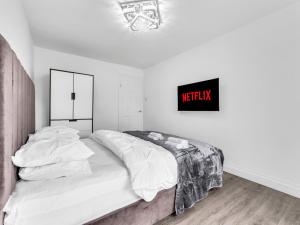 a white bedroom with a bed and a sign on the wall at LODGEselect in Thamesmead