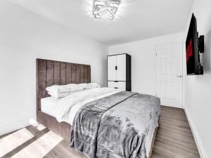 a bedroom with a large bed with a wooden headboard at LODGEselect in Thamesmead +14 photos