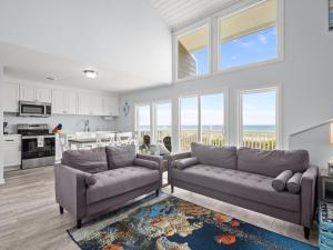 a living room with two couches and a kitchen at Oceanfront vacation home - EAST in Emerald Isle