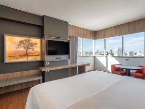 a hotel room with a bed and a flat screen tv at Mercure Uberlândia Plaza Shopping in Uberlândia