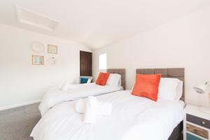two beds in a room with white and orange pillows at Mill View-an idyllic base to explore The Cotswolds in Northleach