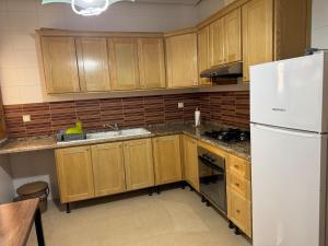 a kitchen with wooden cabinets and a white refrigerator at Résidence Tasnim Ennasr in Ariana +13 photos