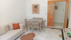 a living room with a table and a white couch at Résidence Tasnim Ennasr in Ariana