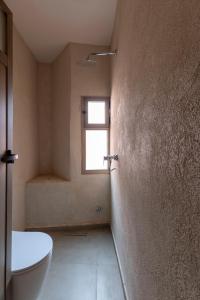 a bathroom with a toilet and a window at Taghazout Waves Surf camp & Hotel in Aourir +2 photos