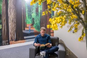 a man sitting in a chair reading a book at Rock Solid Backpackers Rotorua in Rotorua