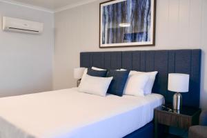 a bedroom with a large bed with white and blue pillows at Victory Hotel Motel Gympie in Gympie