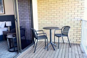 a table and two chairs on a porch with a bed at Victory Hotel Motel Gympie in Gympie
