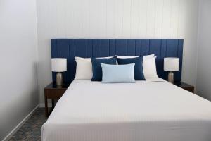 a large bed with a blue headboard and two lamps at Victory Hotel Motel Gympie in Gympie +5 photos