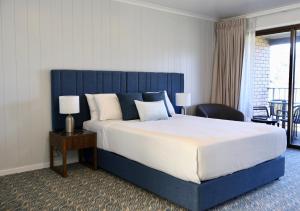 a bedroom with a large bed with a blue headboard at Victory Hotel Motel Gympie in Gympie