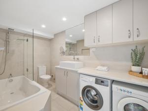 a bathroom with a washing machine and a sink at Wharf Lodge River View Apartment in Maroochydore