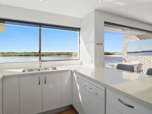 a kitchen with white cabinets and a large window at Wharf Lodge River View Apartment in Maroochydore +7 photos