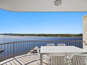 a white table and chairs on a balcony with the water at Wharf Lodge River View Apartment in Maroochydore