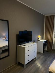 a bedroom with a dresser with a tv and a mirror at modernes gemütliches Apartment in Gießen