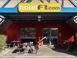 a hotel iguana with picnic tables in front of a building at hotelF1 Limoges in Limoges